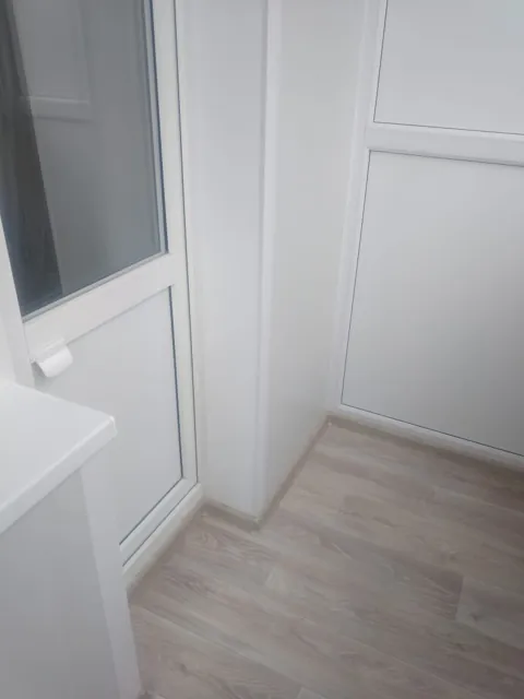 Белые панели и ламинат на балконе
